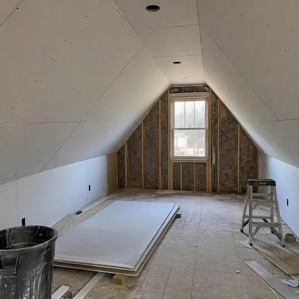 Attic room with new drywall installed on sloped ceilings