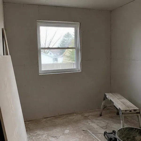 Bedroom drywall installed neatly around a window opening