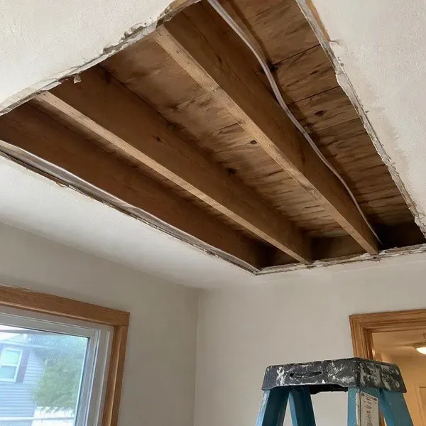 Ceiling drywall opened to exposed joists during water damage repair