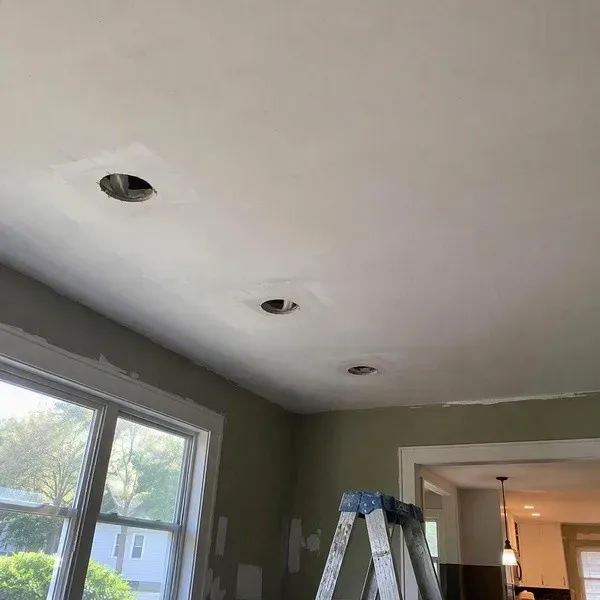 Ceiling with three unused recessed light cutouts before repair