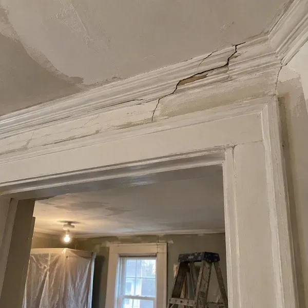 Cracked plaster crown moulding above a doorway before repair
