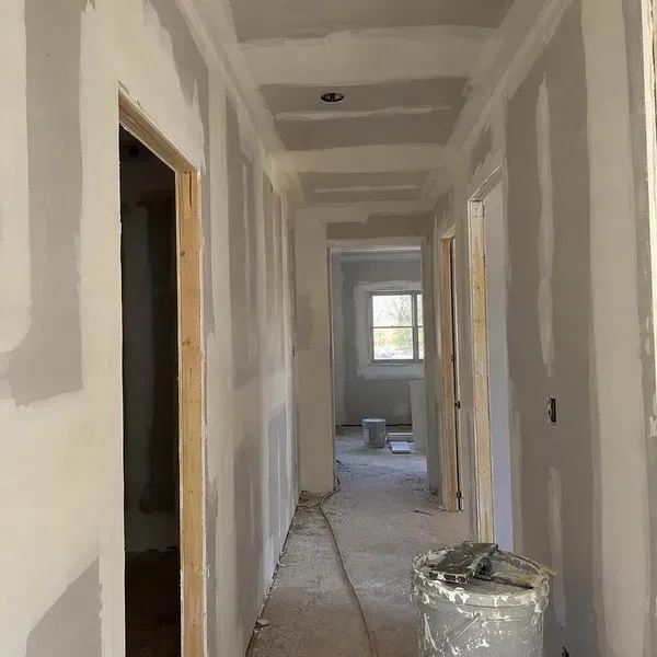 Wide coats of drywall mud feathered over taped joints along a hallway