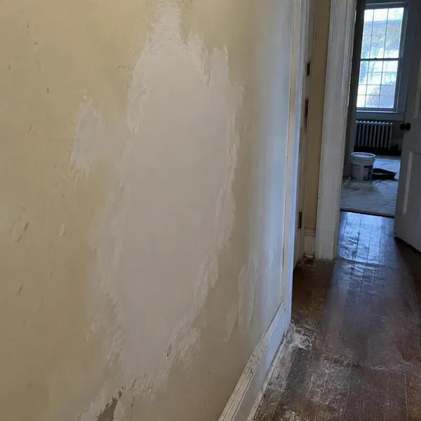 Large plaster patch on an older hallway wall in a historic home