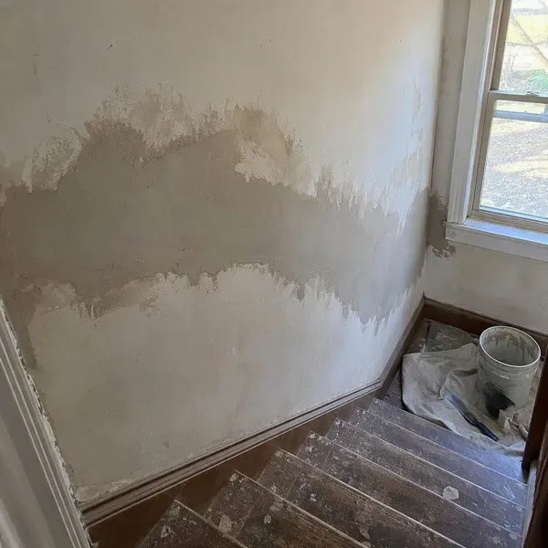 Fresh plaster repair along a stairwell wall in an older home