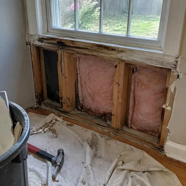 Water-damaged drywall removed below a leaking window to dry the wall cavity